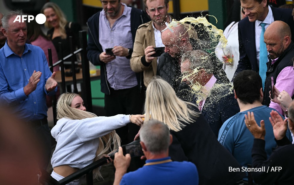 A person throws a drink in the face of a politician